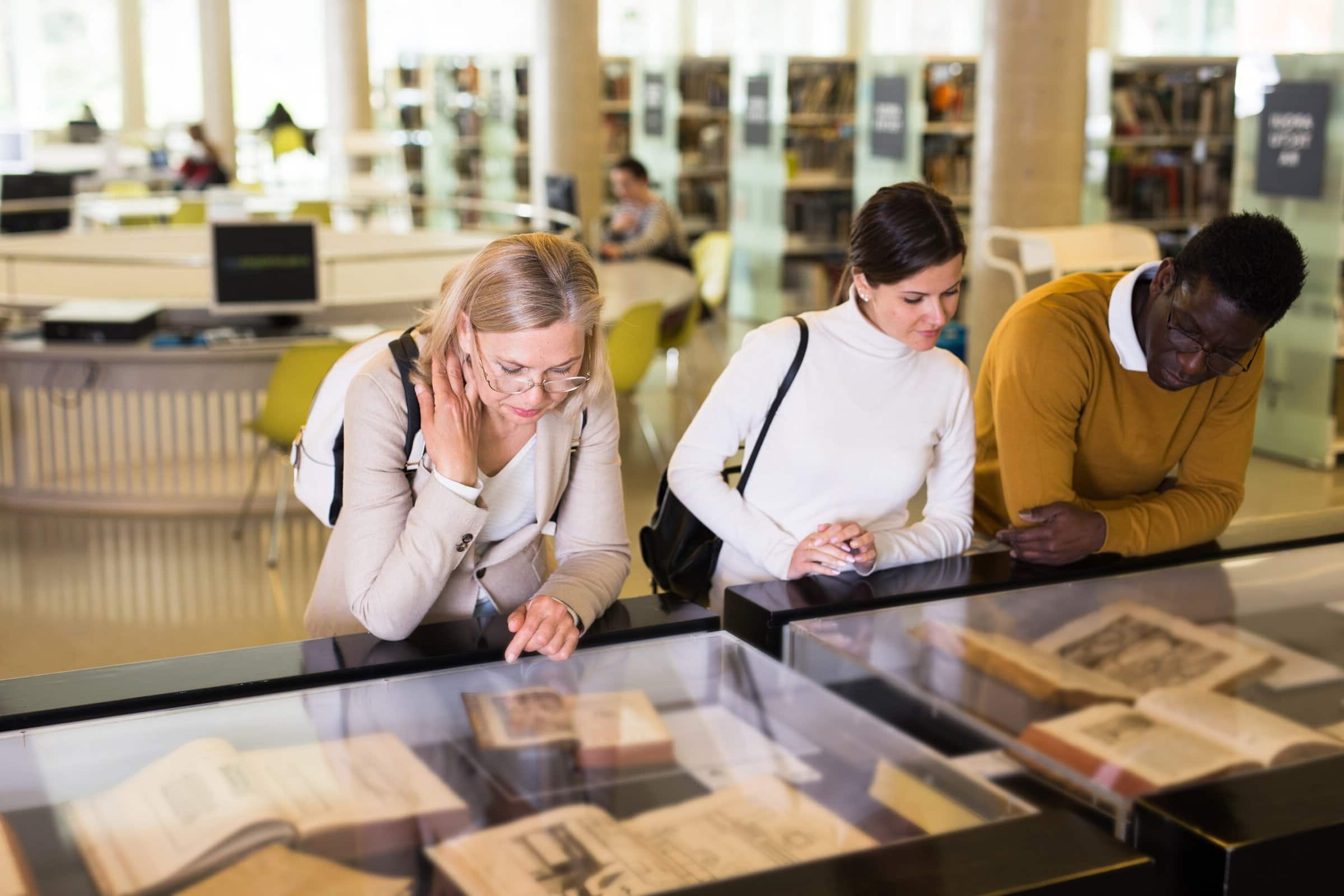 Teacher,And,Adult,Students,View,Rare,Books,In,A,Library